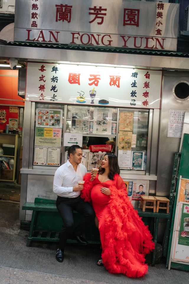 A couple poses in front of a Chinese restaurant storefront, with the woman wearing a flowing red dress.