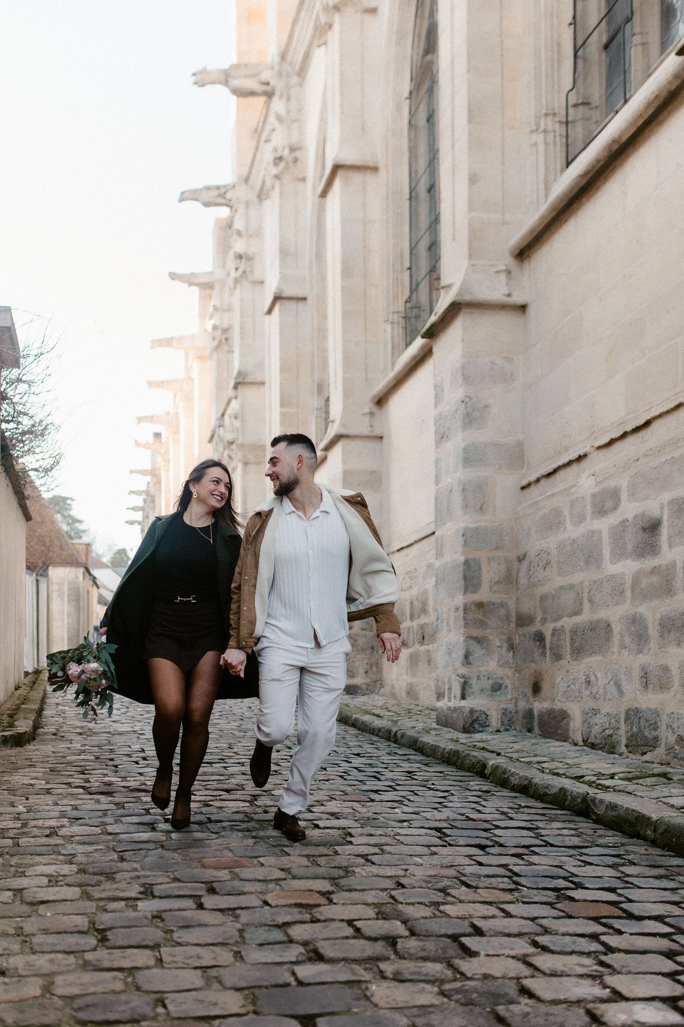 Couple d'amoureux en train de courir devant l'église de Montfort l'Amaury dans les yvelines