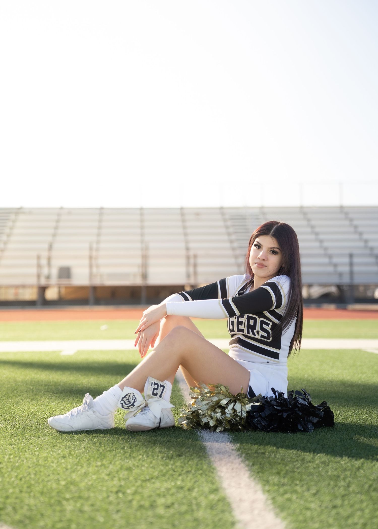 CyPark High cheerleader posing on football field with pom-poms, smiling in uniform