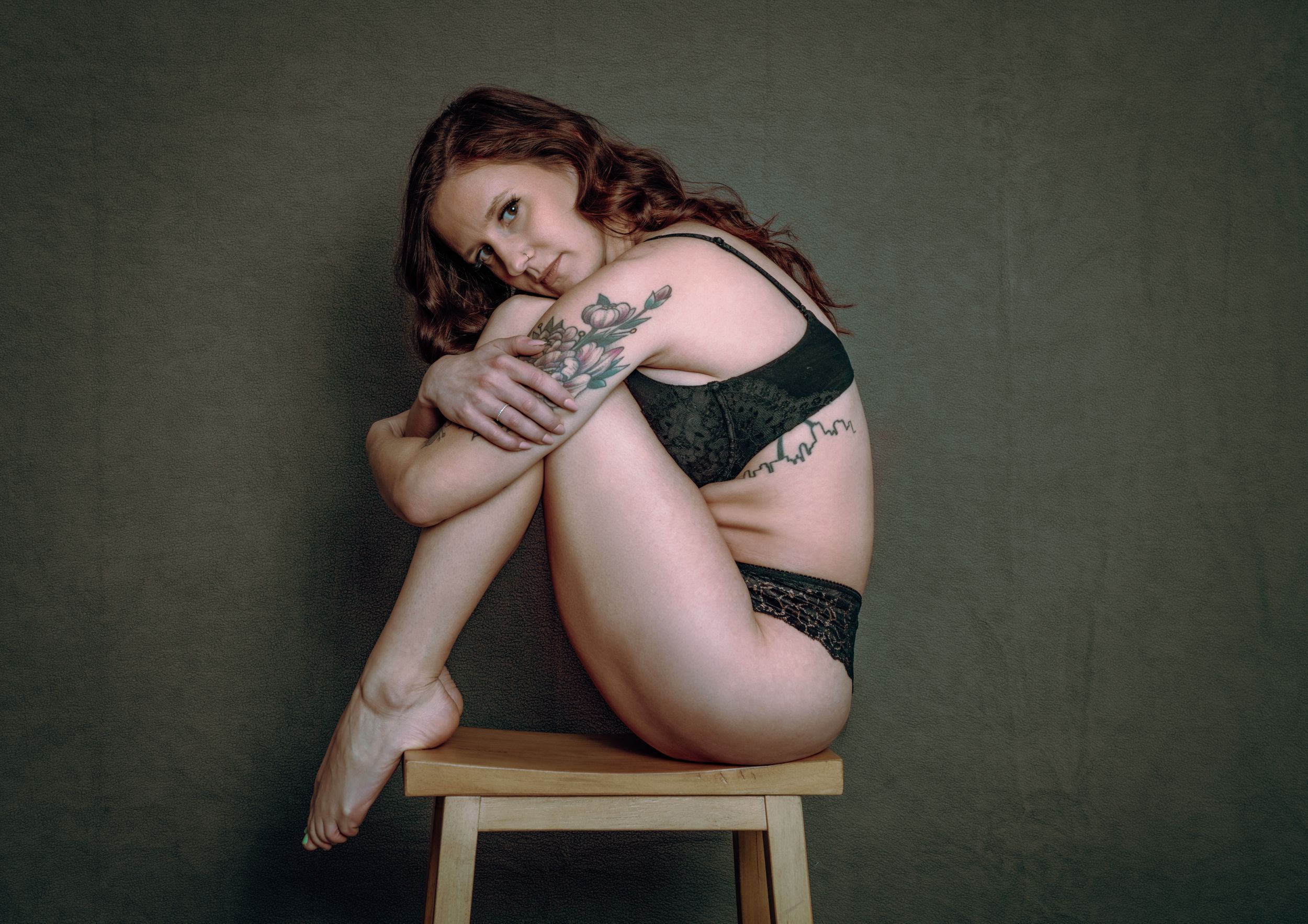 Artistic boudoir photo series showing intimate poses on a wooden chair against a dark textured wall.