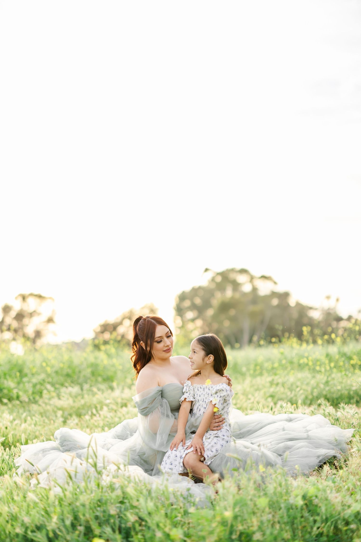 Dreamy outdoor portrait session in a grassy field at golden hour with ethereal white gowns.