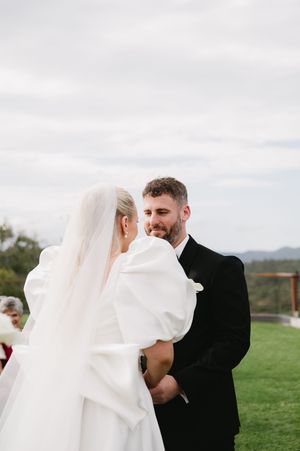Intimate moment between newlyweds during outdoor wedding ceremony.