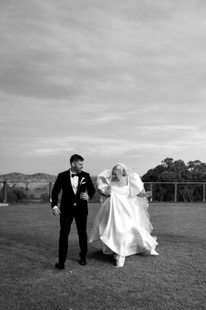 Black and white wedding photos showing a couple running and playing in an open field.