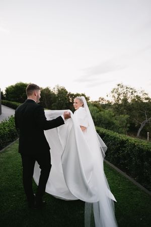 Couple dancing together on grass during wedding photoshoot.