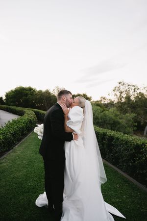 Intimate wedding couple moment captured in lush garden setting at dusk.
