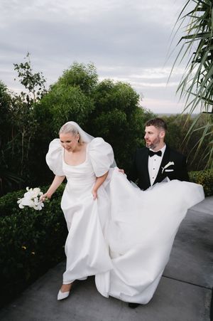 Newlyweds walking along pathway with flowing white wedding dress in motion.