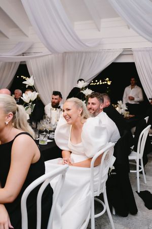 Wedding guests laugh and dance together under an elegant white tent with draped fabric ceiling.