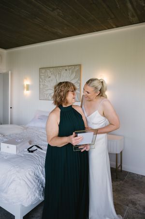 Two people in formal attire having conversation in bedroom with white walls and dark ceiling.