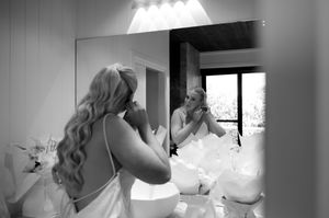Black and white photo showing bridal preparation moments with soft window lighting.