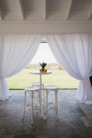 White draped curtains and elegant bistro tables create an intimate outdoor seating area.
