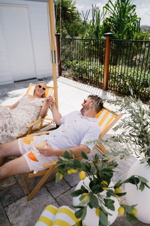 Person relaxing in a striped deck chair surrounded by citrus plants on a sunny patio.