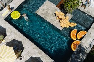 Aerial view of a luxurious swimming pool with citrus fruits and refreshments arranged along the edge.