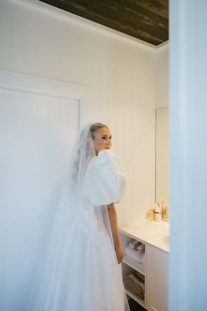 A flowing white wedding dress with delicate veil captured in a bright interior space.