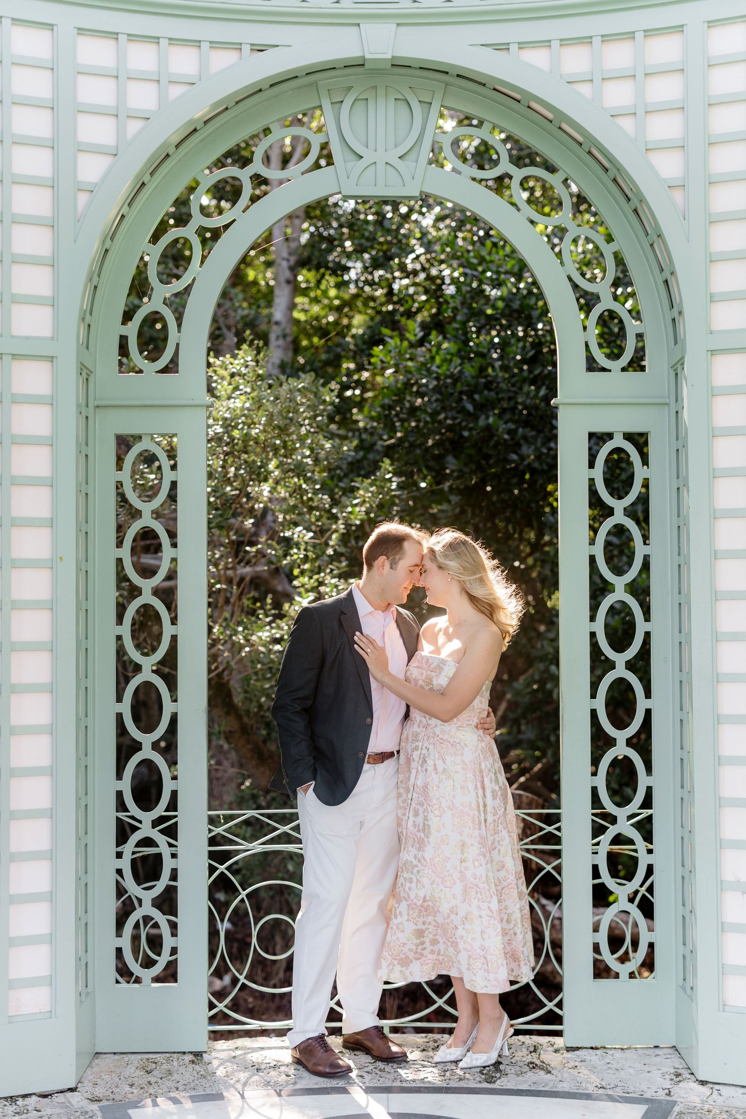 Couple sharing intimate moments under mint green latticed garden gazebos.