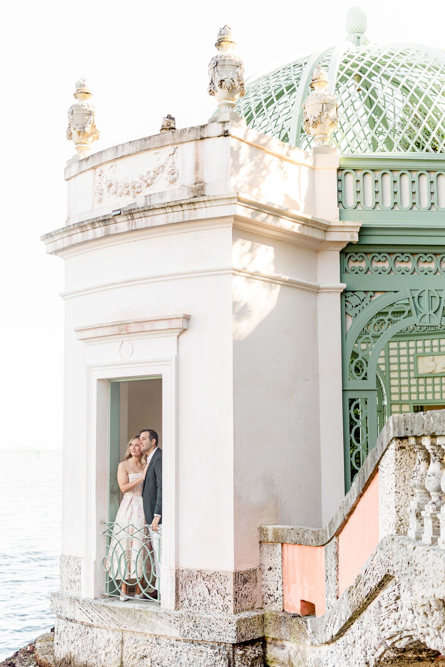 Historic white stone architecture with green domed features creates a romantic setting.