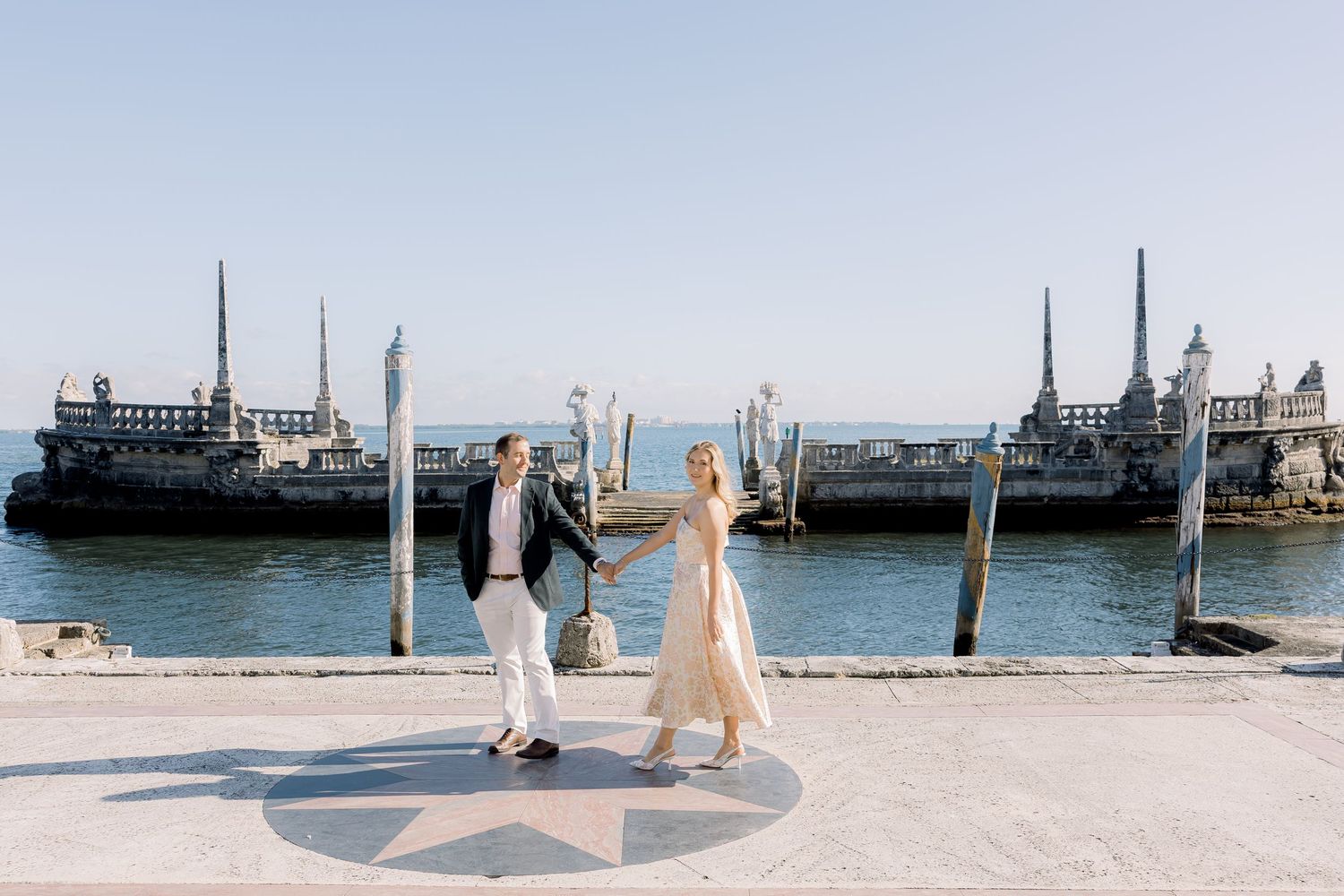 Romantic waterfront engagement photos with sailboats and pier in the background.
