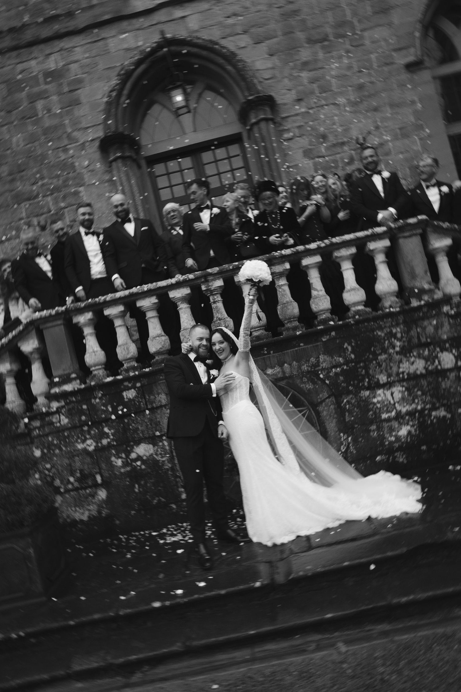Black and white wedding party photos lined up against stone wall showing progression of formal group poses.