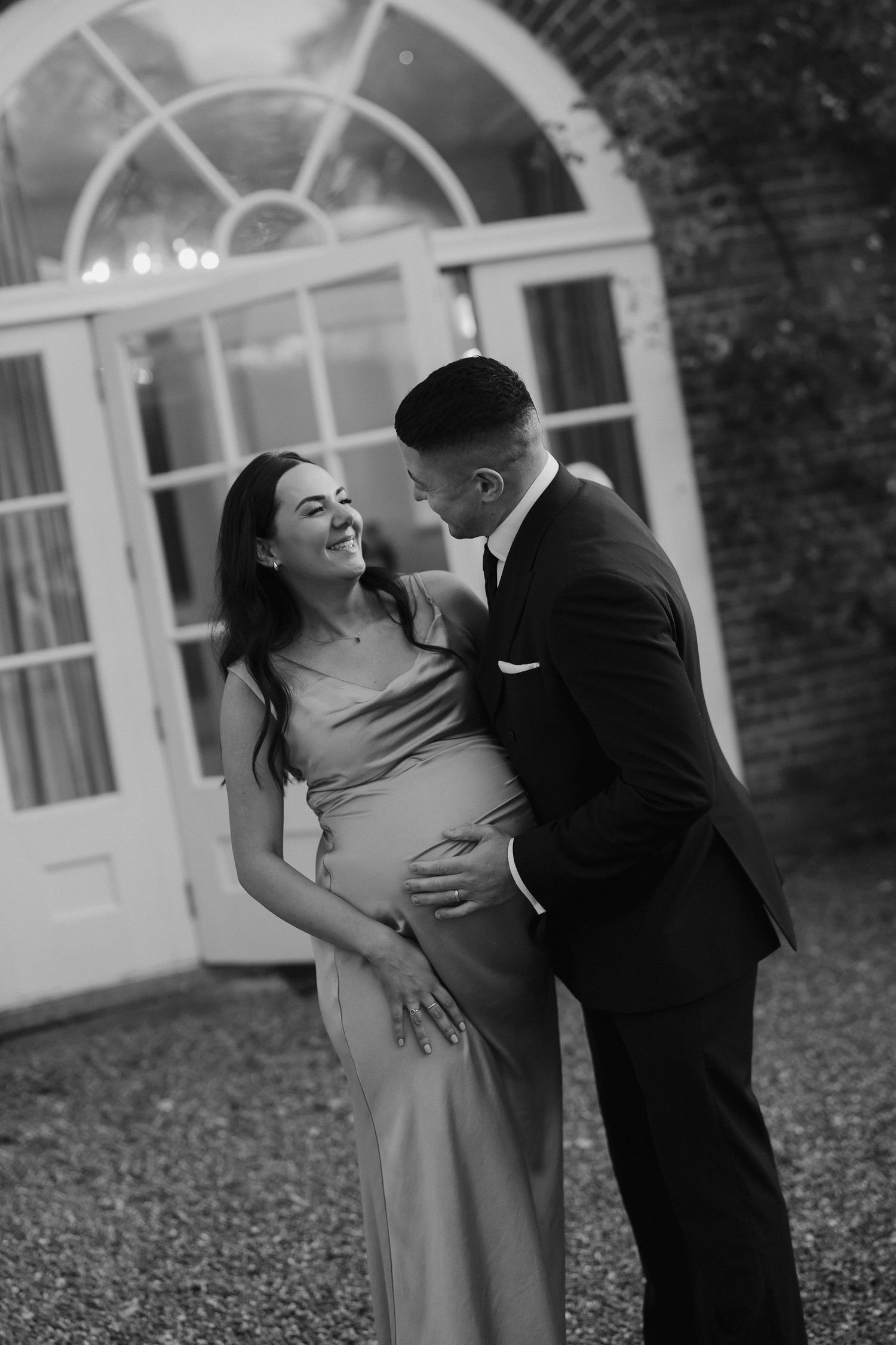 bridesmaid and partner smiling at each other in the gardens outside Iscoyd park
