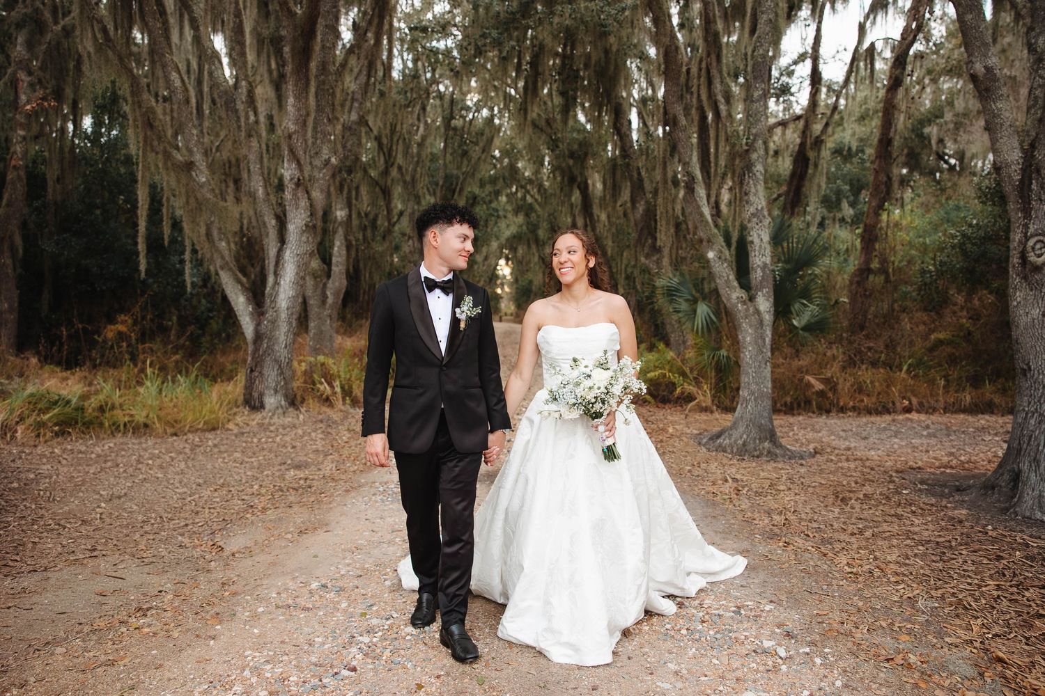 A couple exchanges vows at an outdoor beach wedding ceremony adorned with vibrant tropical floral arch decor.