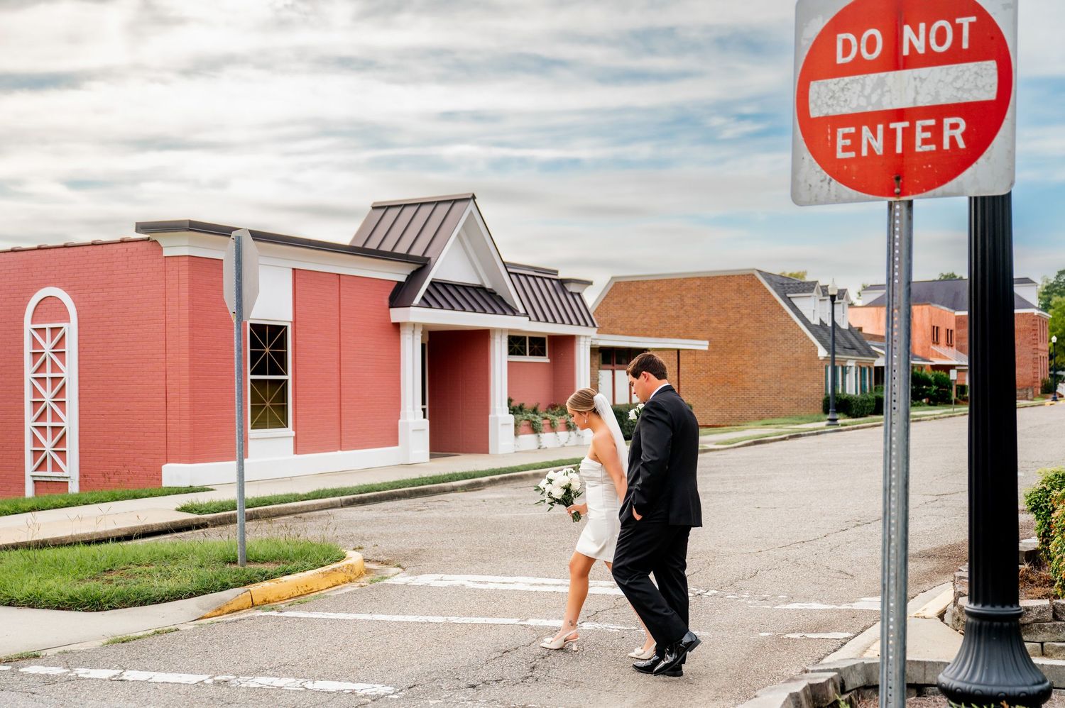 Wedding couple poses playfully near a 'Do Not Enter' sign on their special day.
