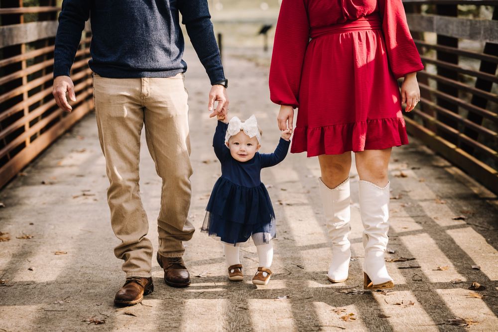 Family members' feet walking together on wooden boardwalk showing coordinated casual footwear.
