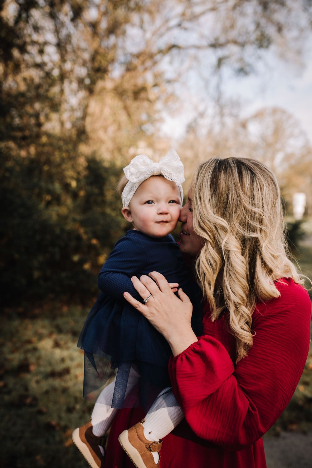 Autumn outdoor portrait session featuring red sweater and navy blue clothing in warm sunlight.