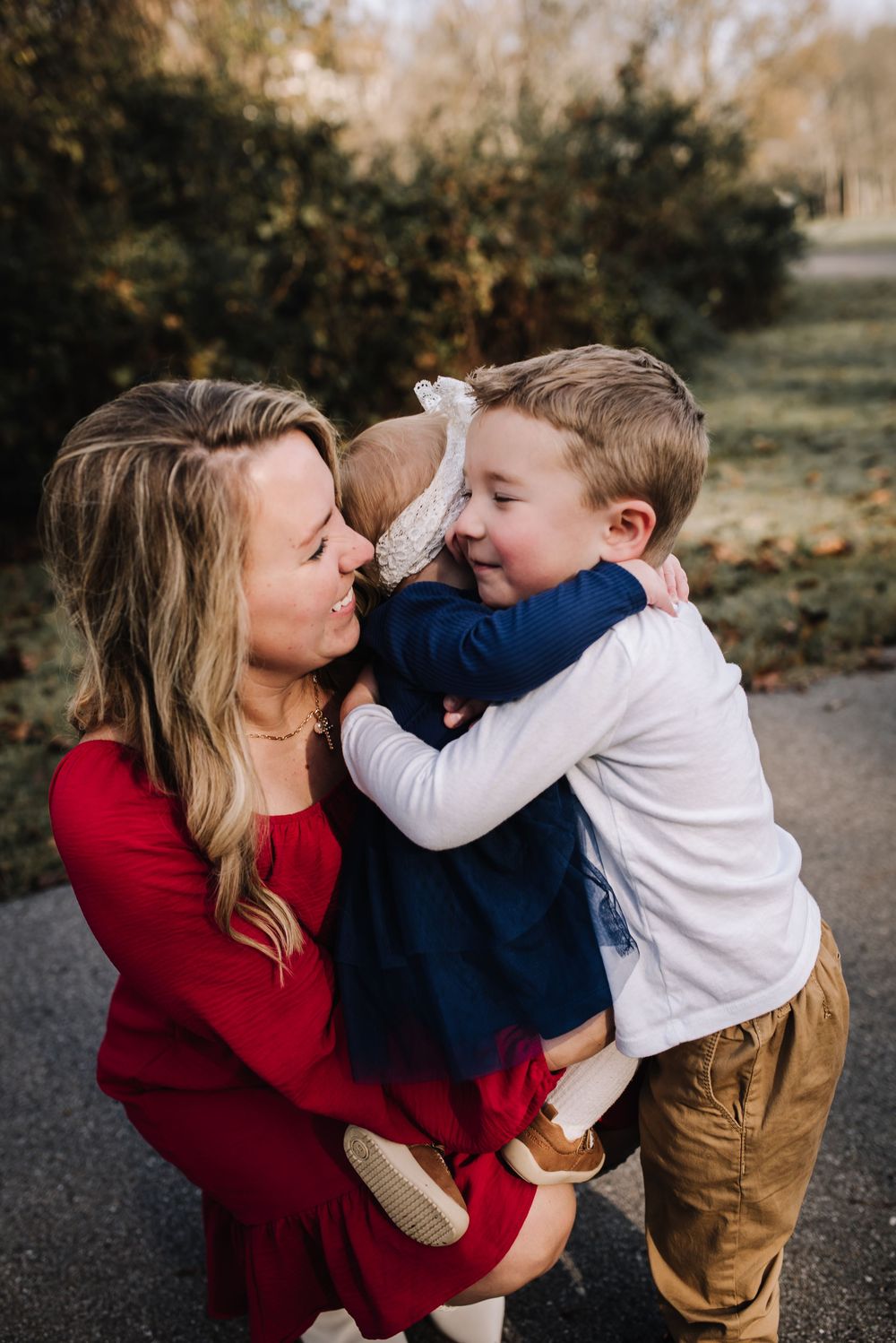 A family shares tender moments and embraces while wearing coordinated outfits outdoors.