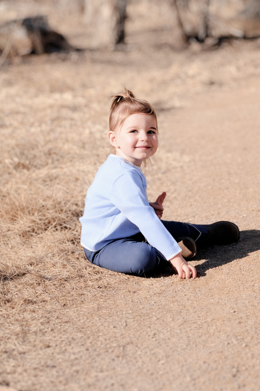 child sitting on dirt path holding carrots content