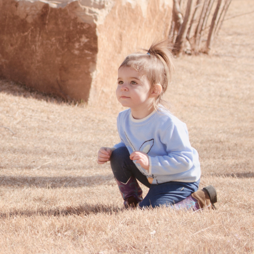 child kneeling down in field