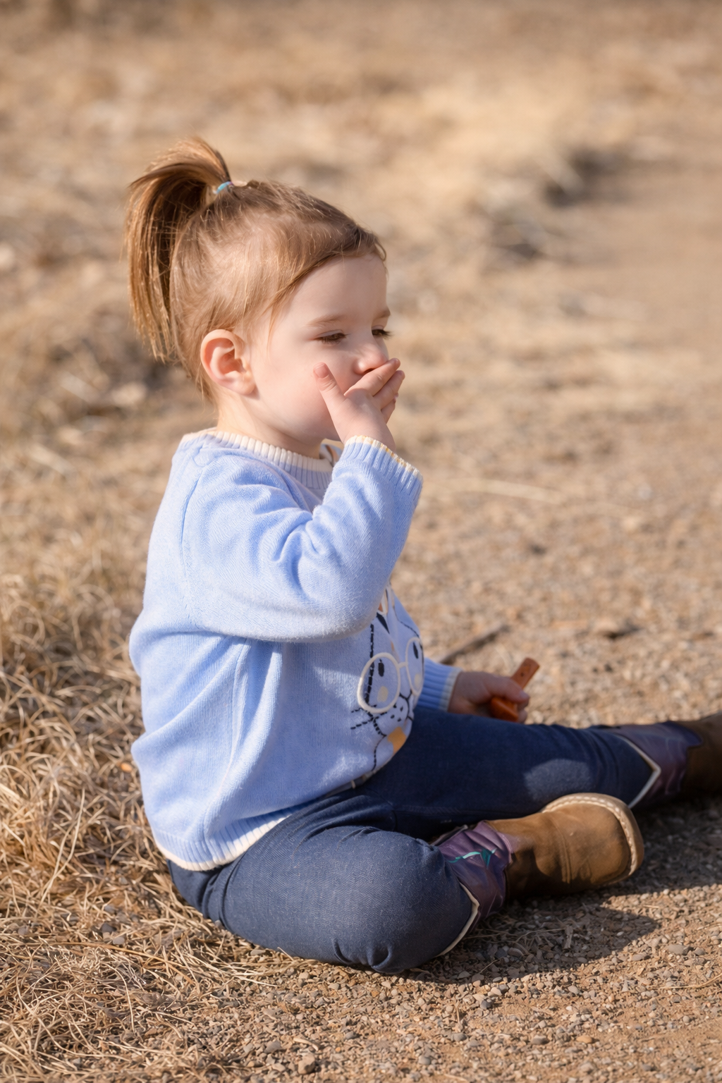 a child sitting on dirt path blowing a kiss