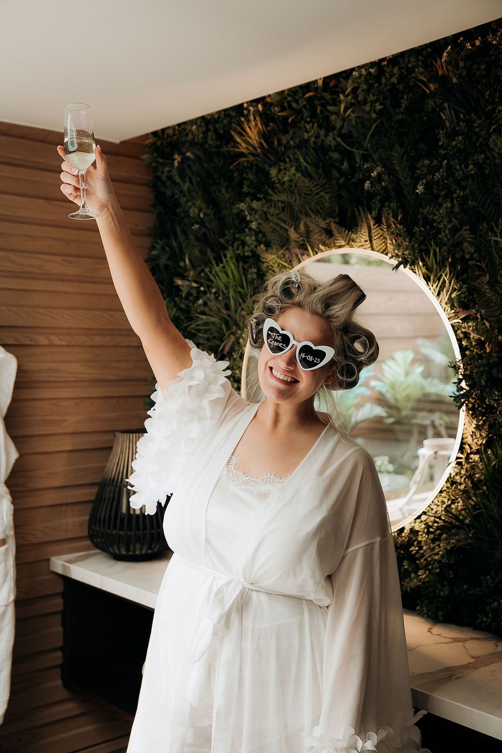 Wedding preparation scene with sunglasses and white robe in natural lighting.