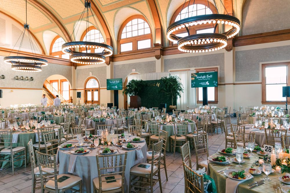 Grand ballroom with arched windows and elegant chandeliers set up for a formal event.