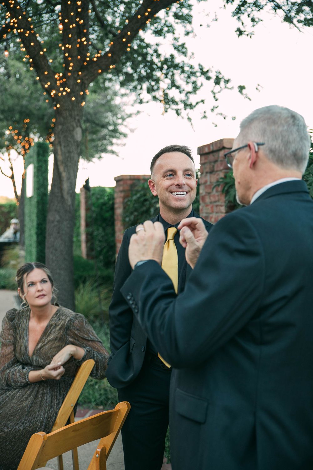 Outdoor event gathering with string lights and trees creating a warm evening ambiance.