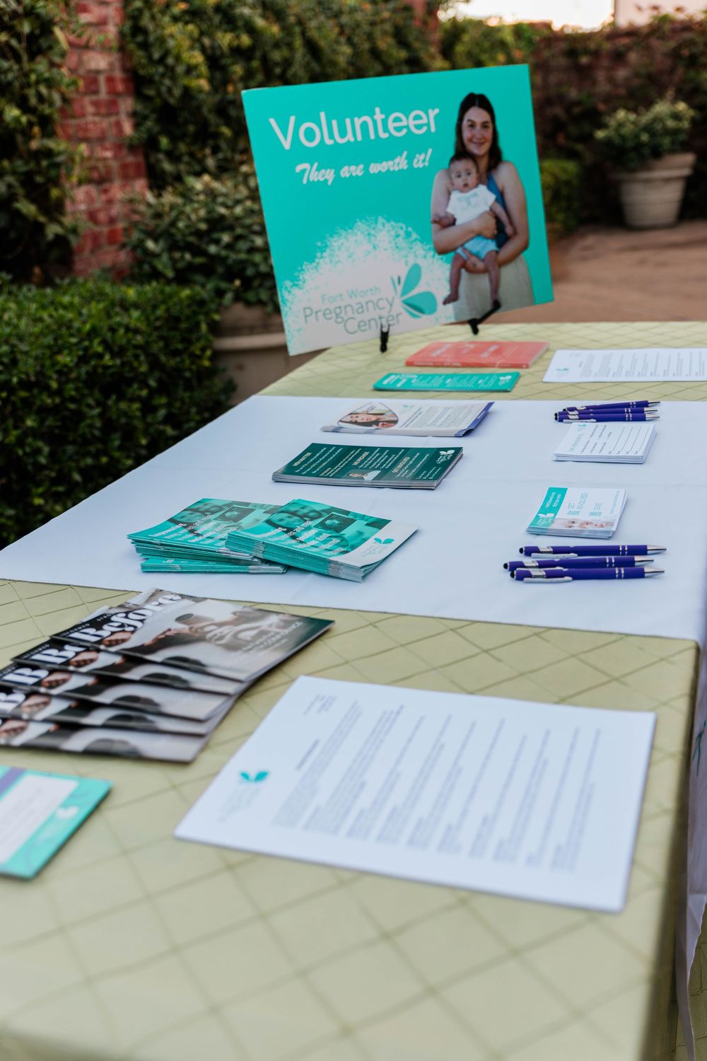 Volunteer registration table with teal signage and informational materials.