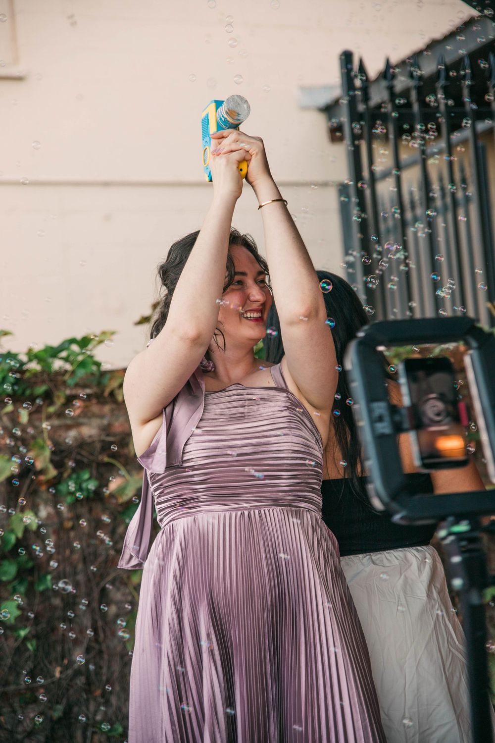 Person in purple pleated dress enjoying drinks at an outdoor celebration.