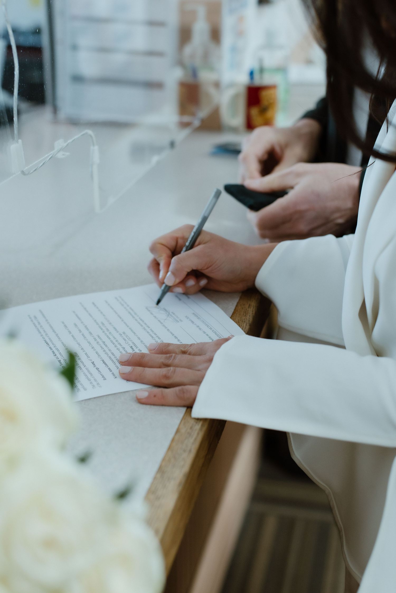 A bride in a white suit dress signs her official marriage certificate during an elopement at the Blaine County Courthouse in Hailey, Idaho.