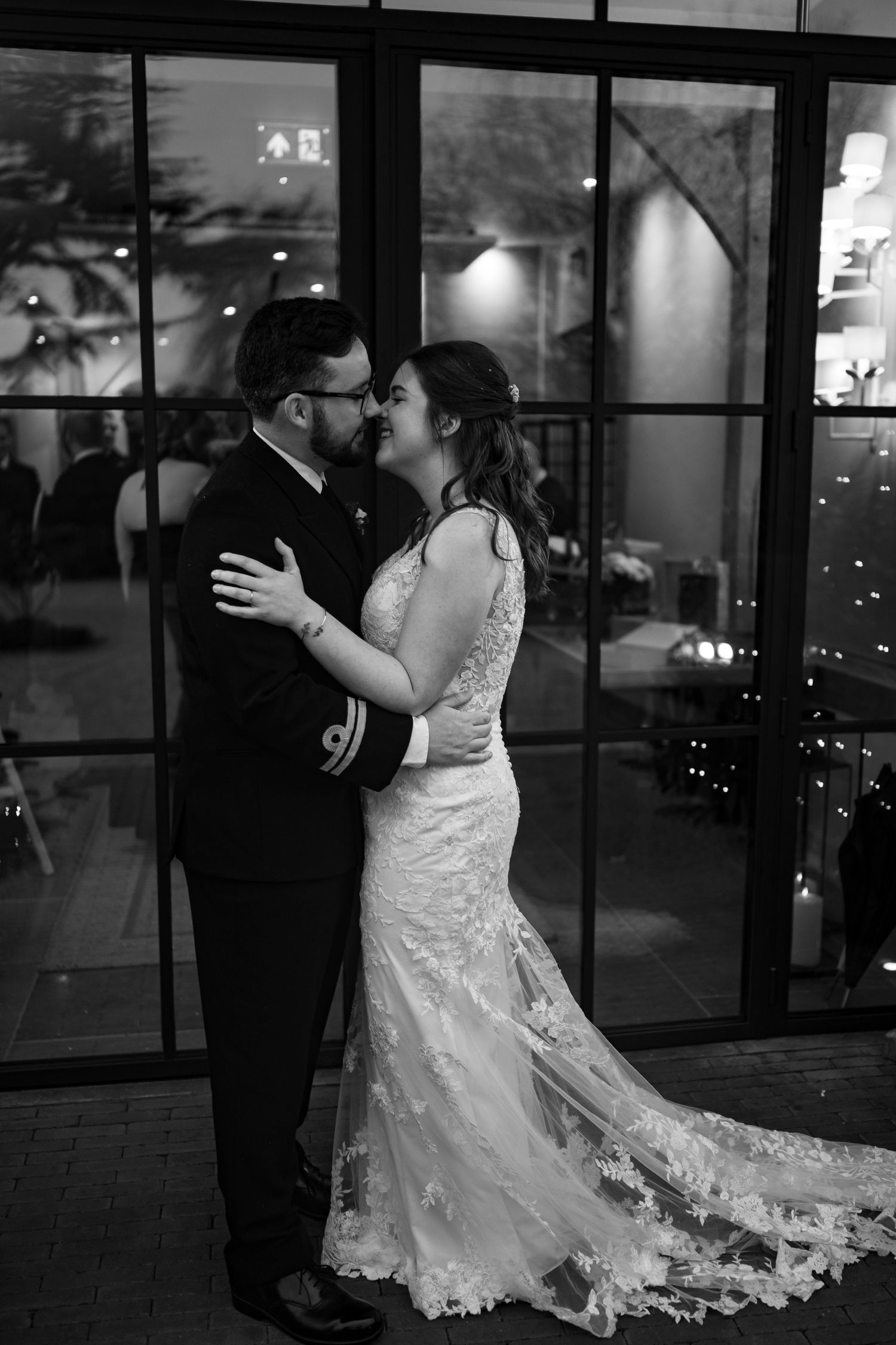 A couple shares a romantic dance at their wedding reception, with the bride's lace gown trailing elegantly behind them.