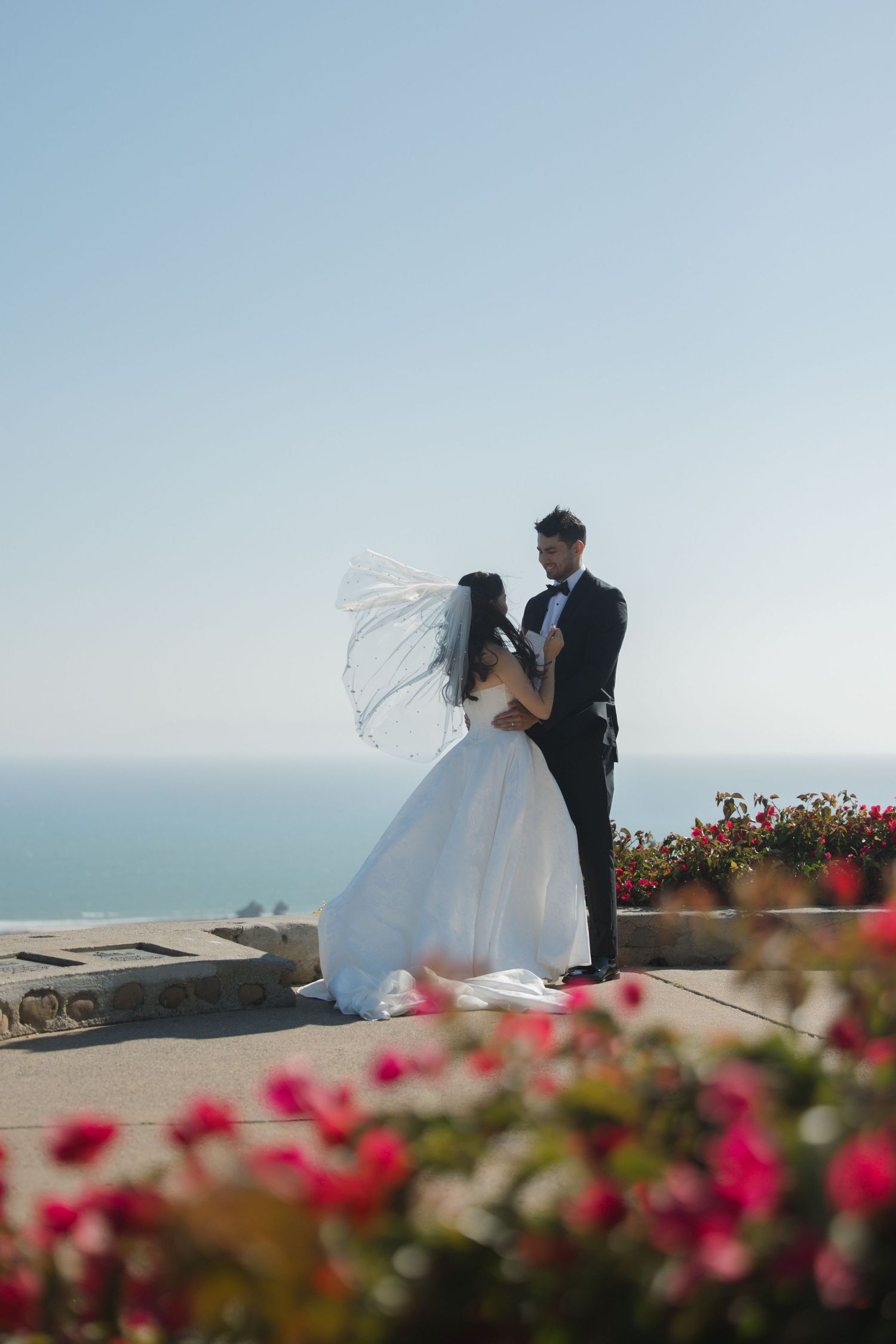 Wedding ceremony at Serra Cross in Ventura with couple reading vows overlooking the ocean and pink florals