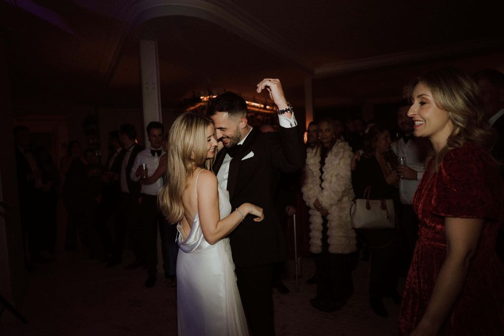 A group of people dancing and socializing at a dimly lit party or nightclub venue.