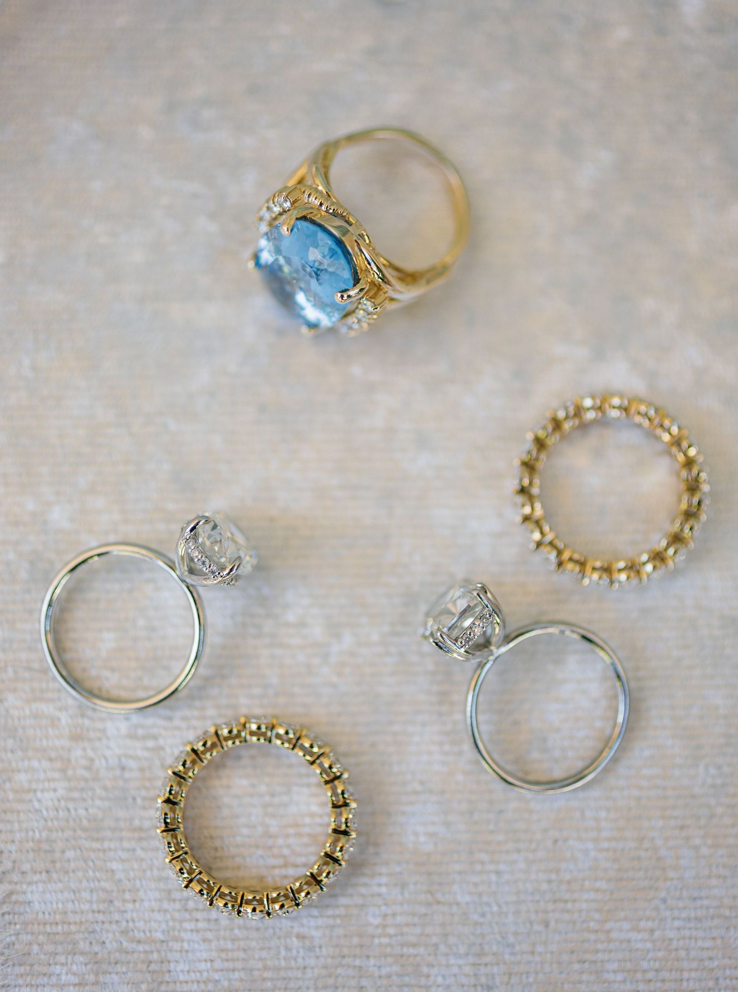 Delicate vintage rings with gemstones and intricate metalwork displayed in a row on a textured surface.