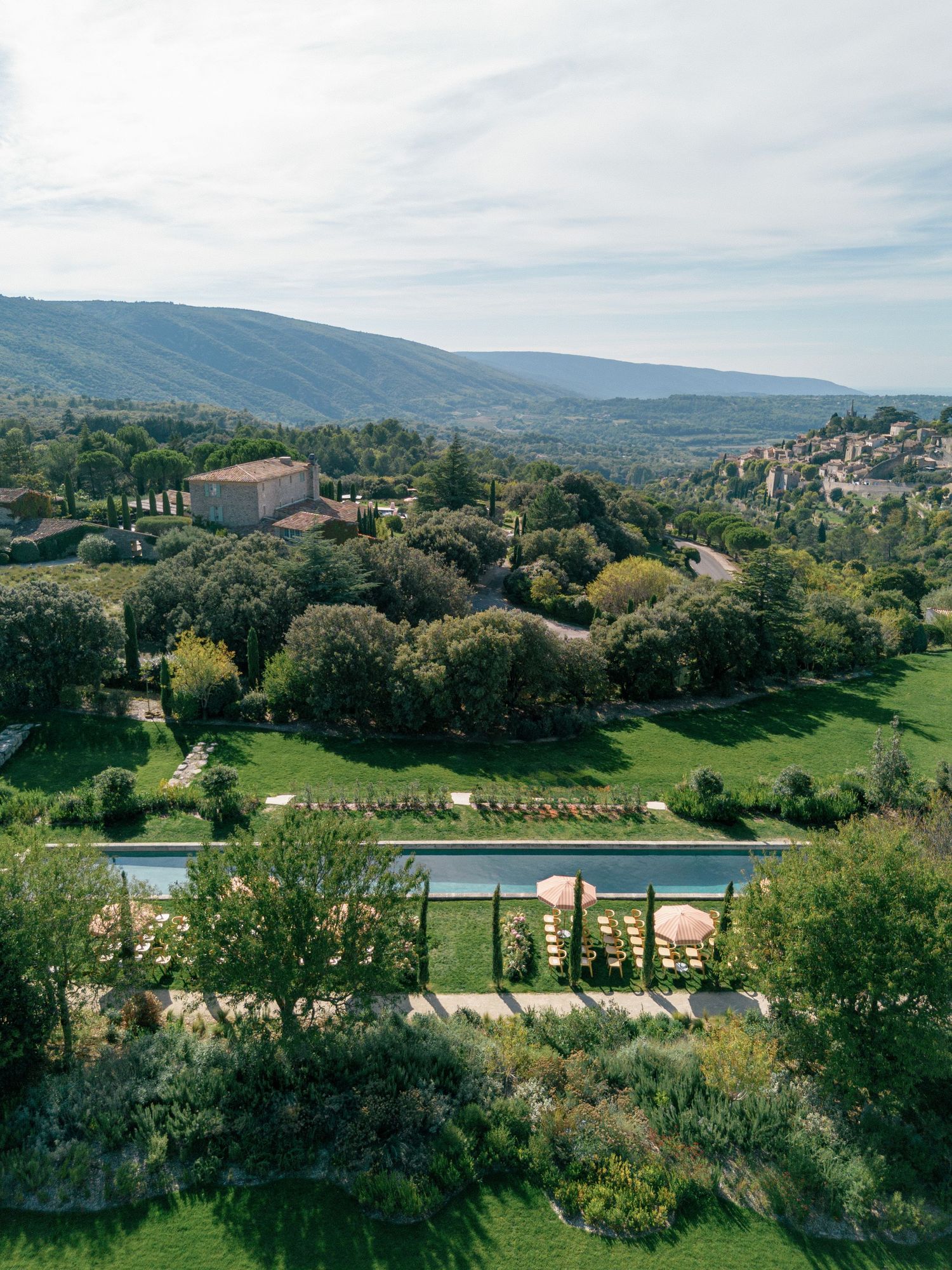Scenic panoramic view of a luxury resort with swimming pools nestled in rolling hills and lush Mediterranean landscape.