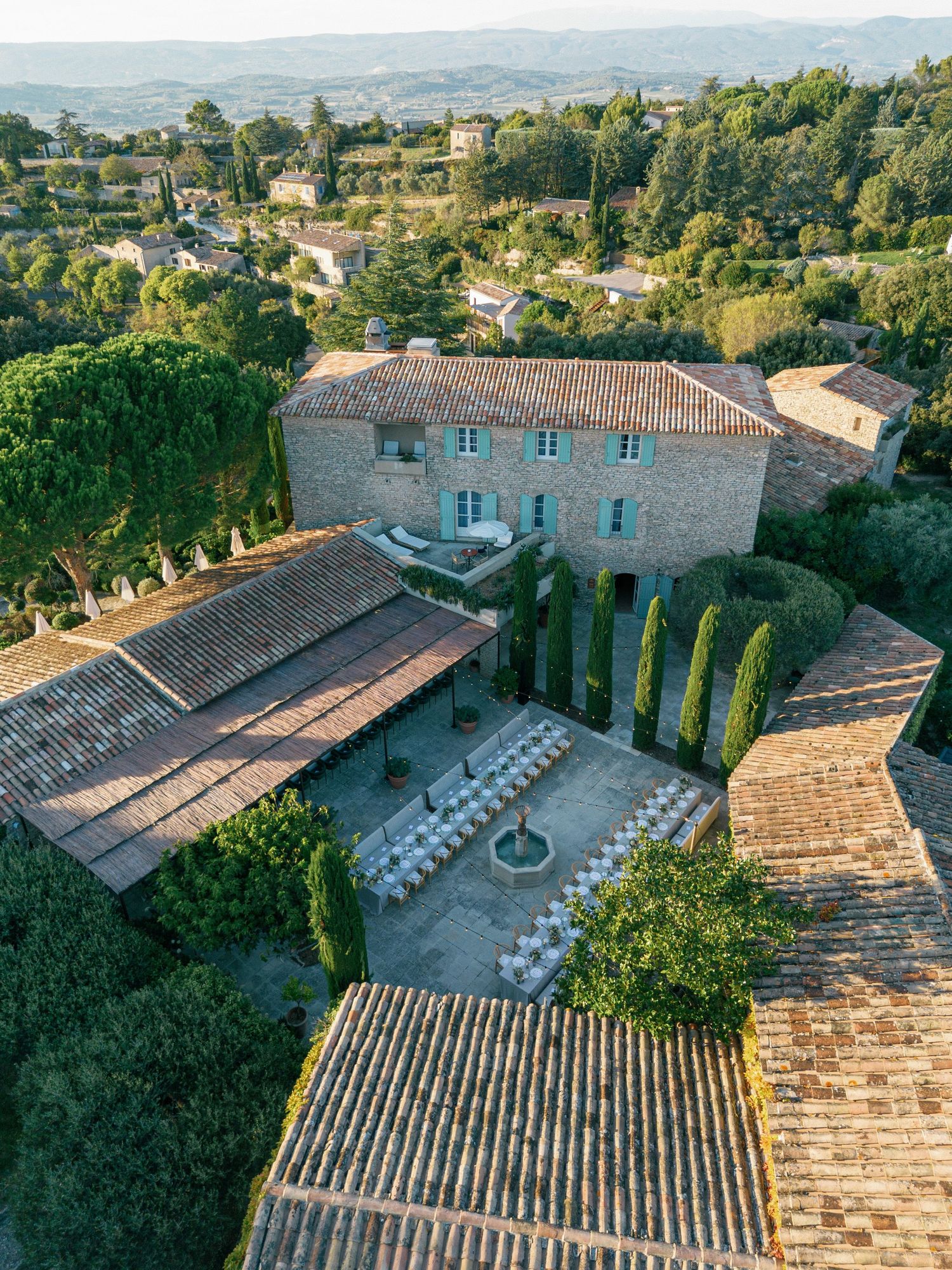 Aerial view of a Provencal villa with stone walls, terracotta roofs and formal courtyard garden in southern France.