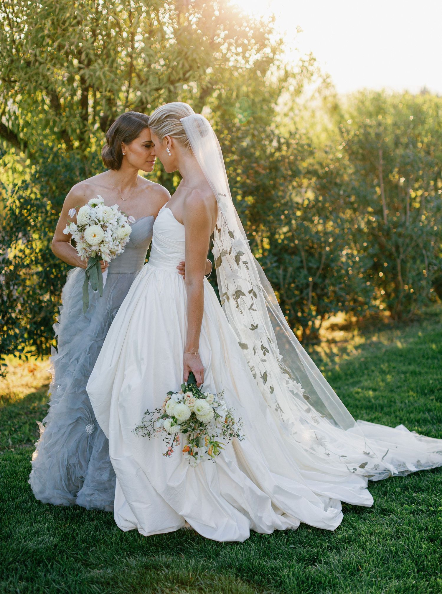 Wedding couple shares intimate moments in a sunlit apple orchard during golden hour photography session.