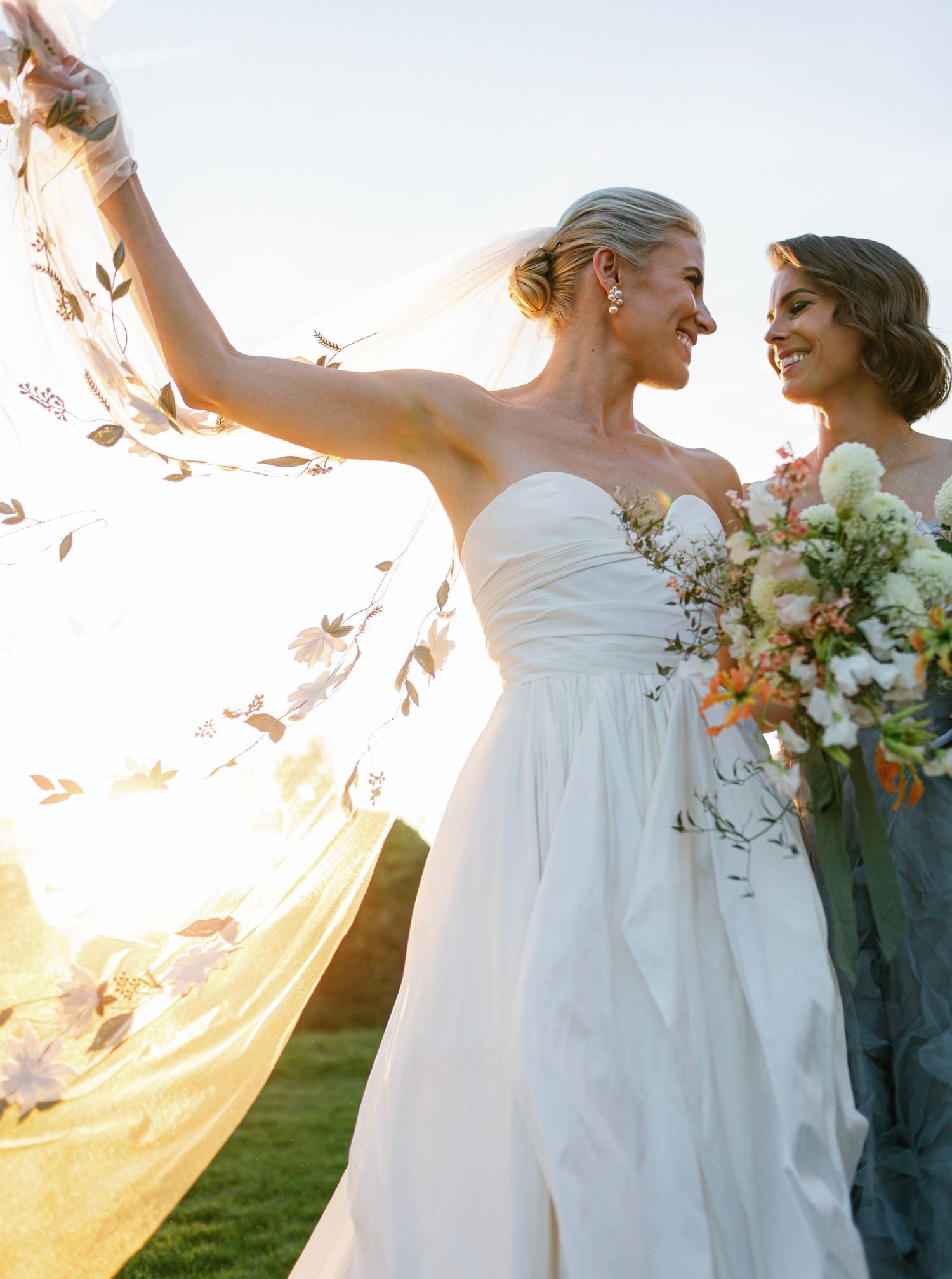 A couple in wedding attire dances together during sunset, their silhouettes backlit by golden light.