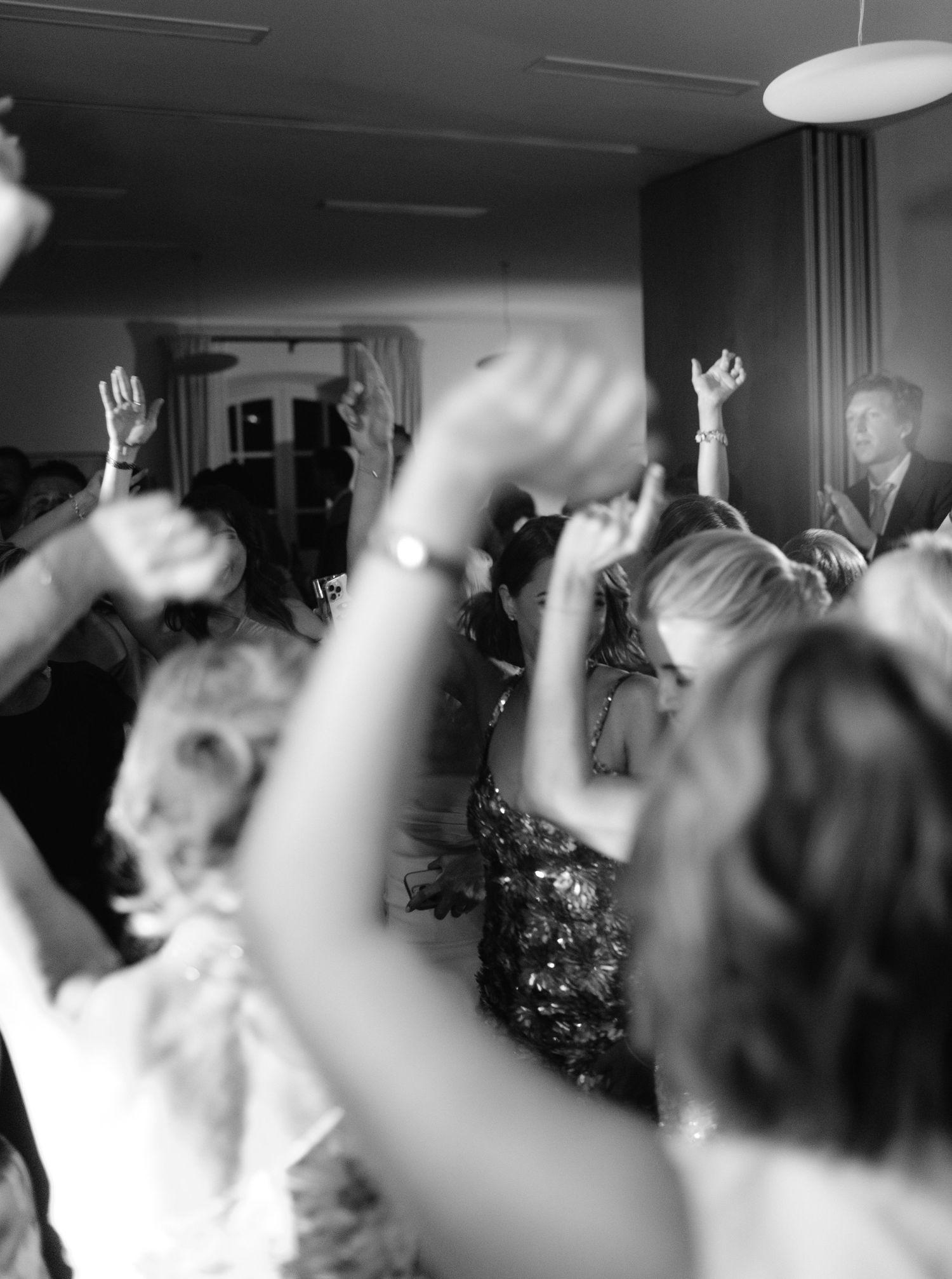A black and white photo of a crowd with raised hands during what appears to be a celebratory moment.