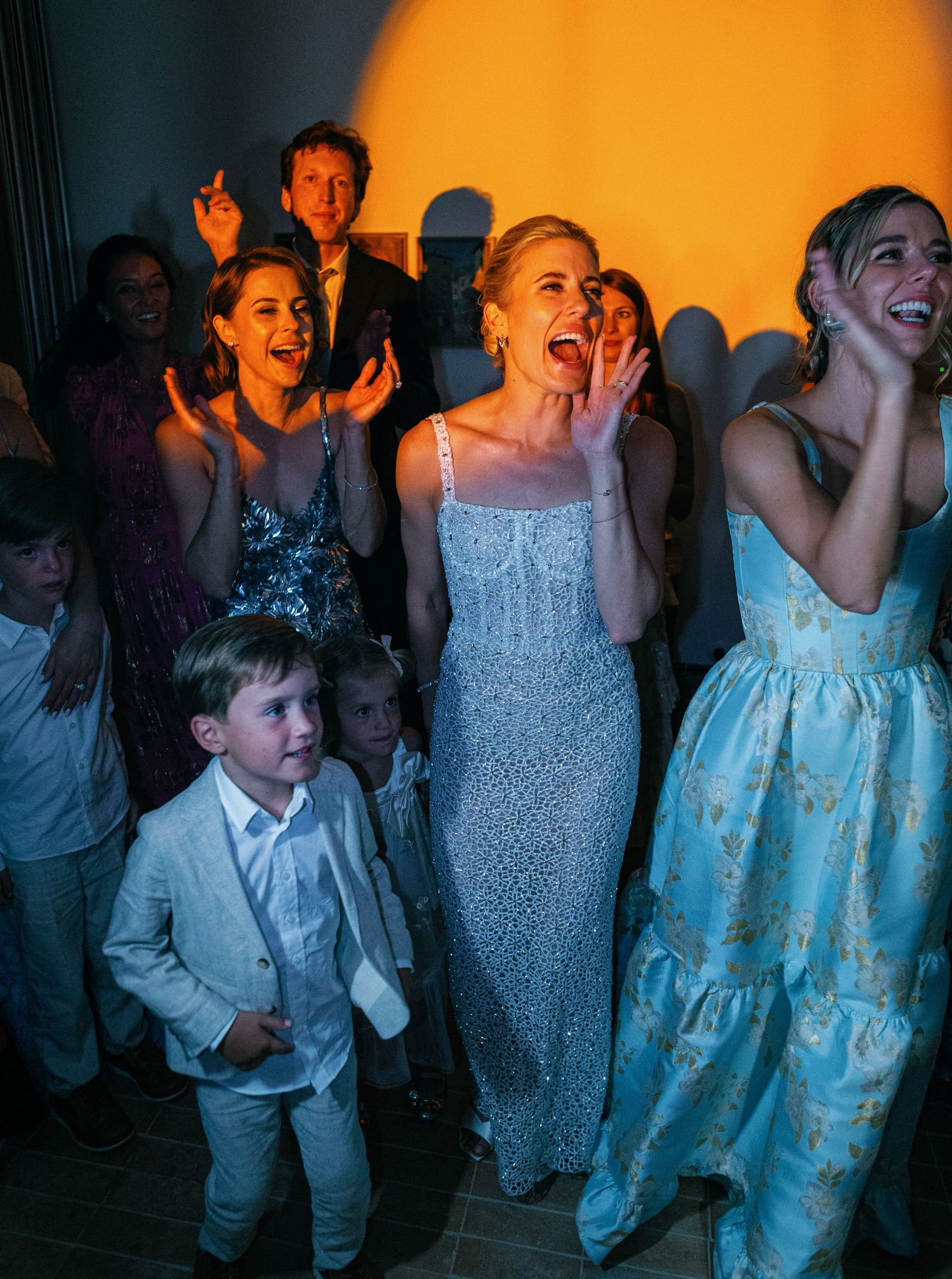 Party guests dancing and enjoying themselves in a dimly lit indoor venue with blue lighting.