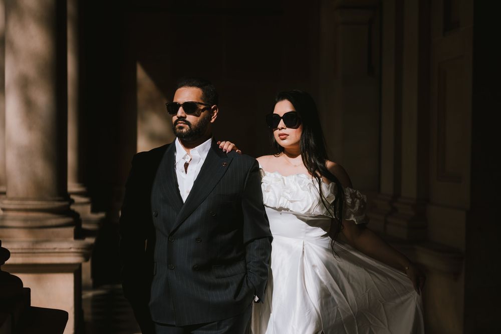 Stylish bride and groom pose in dramatic black and white lighting against classical architecture.