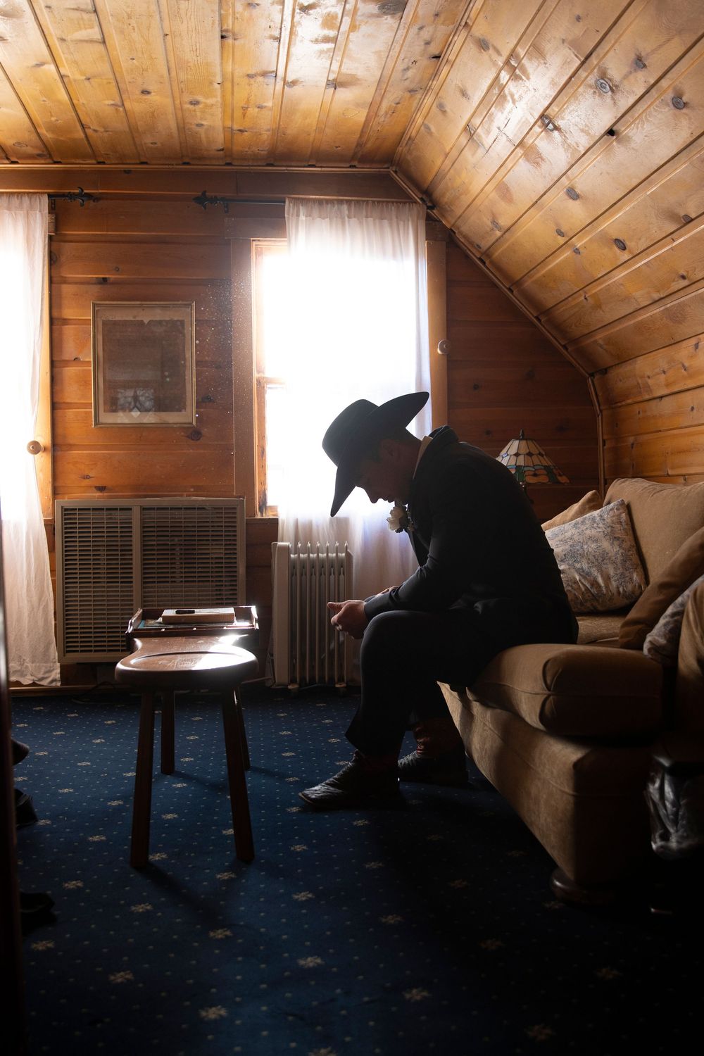 A groom with a cowboy hat and boots on getting ready before the wedding ceremony.