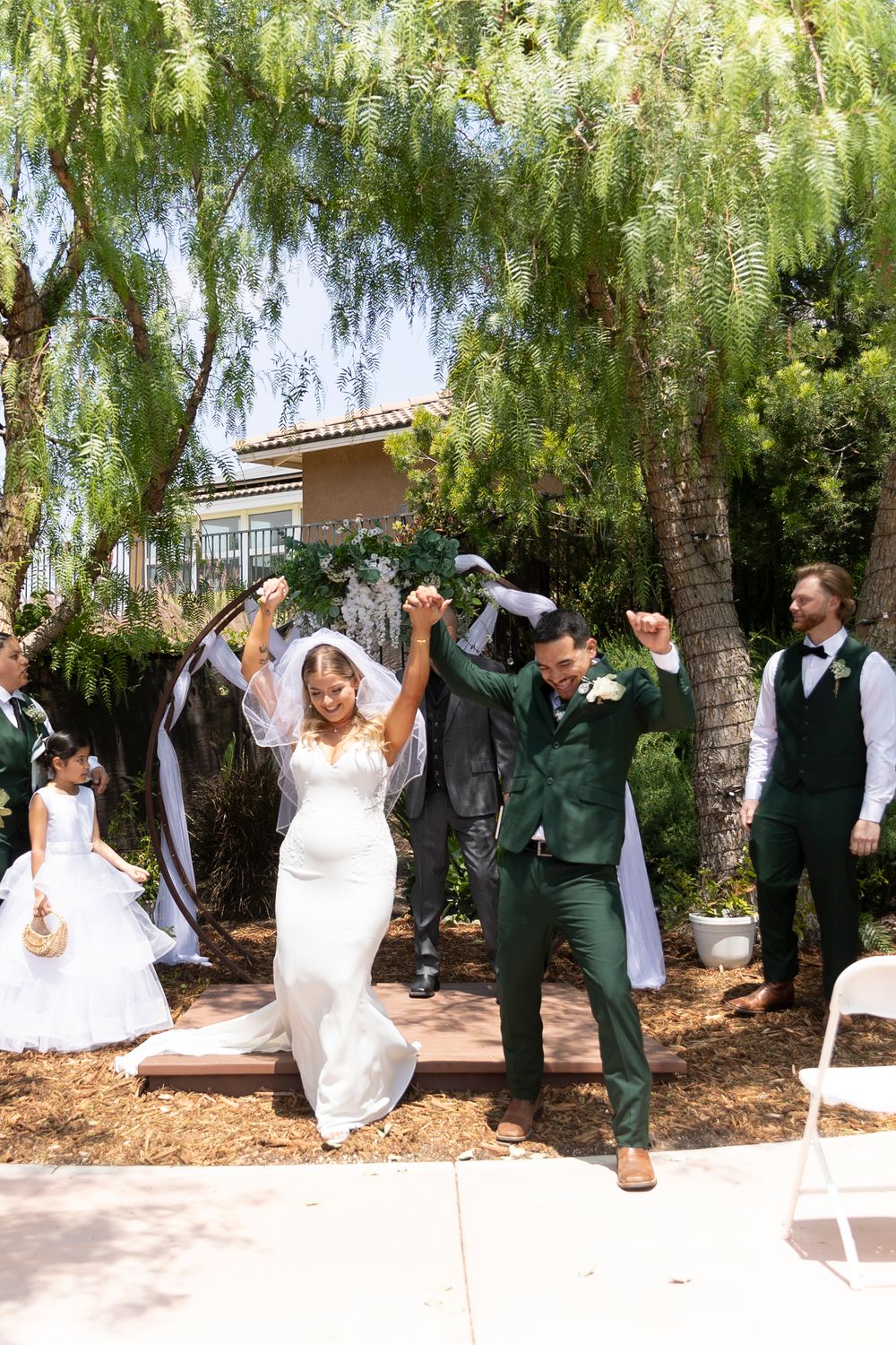 A bride and groom holding hands while raising their arms in the air, walking down the aisle after their wedding ceremony.