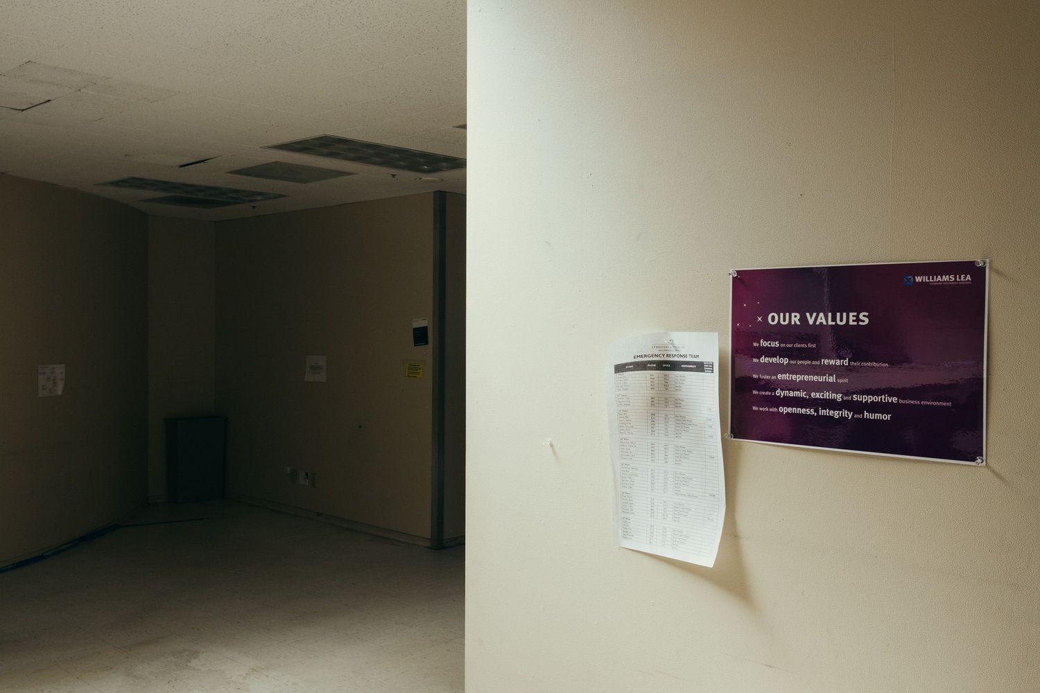 Dimly lit empty hallway with dark walls and ceiling lights creating an atmospheric mood.